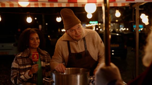 Stephanie staat naast een man die in de soep roert.